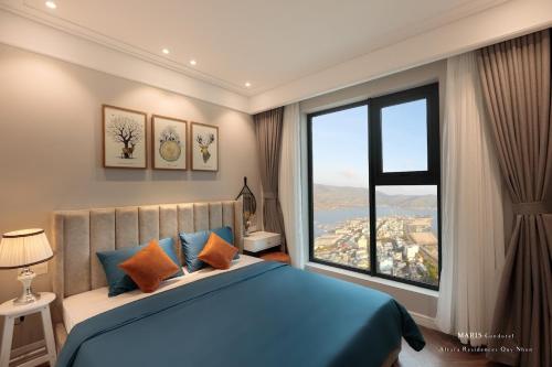 a bedroom with a blue bed and a large window at ALTARA Quy Nhơn - RUBY Luxury Apartment in Quy Nhon