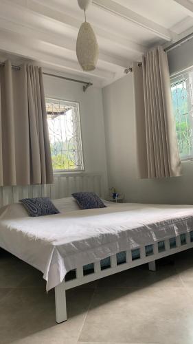 Cette chambre comprend un grand lit et 2 fenêtres. dans l'établissement ชมธารา วิลล่า, à Ranong