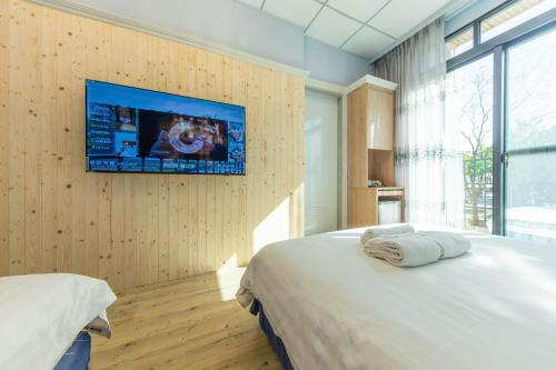 a bedroom with a bed and a tv on a wall at EZ STAY Yancheng in Kaohsiung