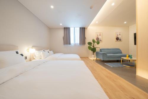 a bedroom with a large white bed and a couch at Browndot Gangneung Station in Gangneung