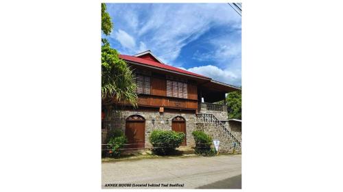 a house with a red roof and wooden doors at Paradores Del Castillo in Taal