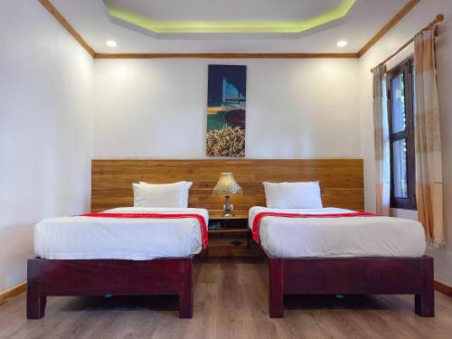 a bedroom with two beds and a table with a lamp at Luang Prabang Villa Oasis in Luang Prabang