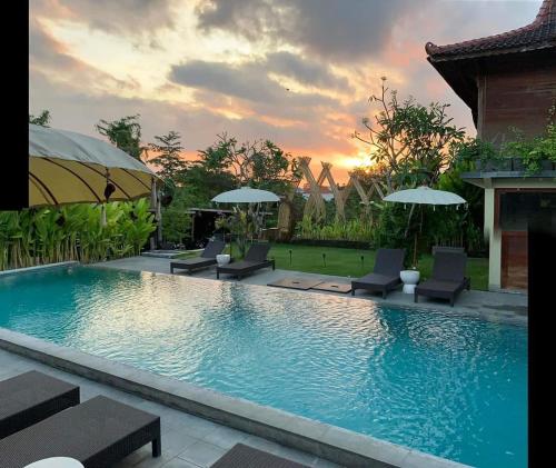 a large swimming pool with chairs and umbrellas at Desaku Bungalows in Canggu