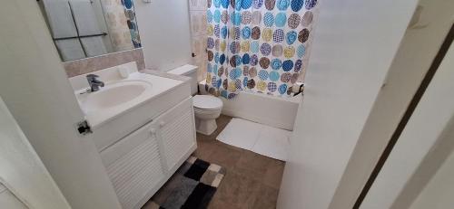 a bathroom with a sink and a toilet and a shower curtain at Seaview Property 3B Two Bedroom Apt Hasting Towers in Bridgetown