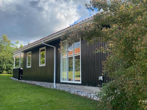 ein Haus mit schwarzen Seitenwänden und Fenstern in der Unterkunft Skønt sommerhus tæt på skov, strand og hyggeligt havnemiljø in Bønnerup