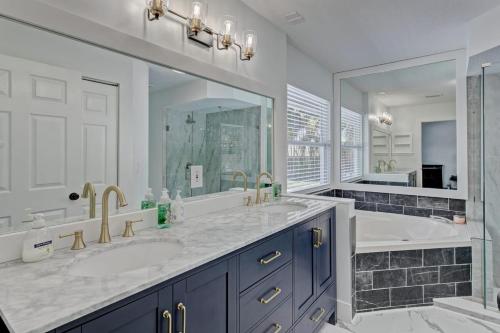 a bathroom with two sinks and a tub and a large mirror at Private Heated Pool Bbq Patio King Beds in Royal Palm Beach