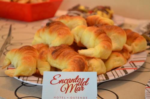 a plate of croissants on a table with a sign at Encanto Del Mar in Ostende