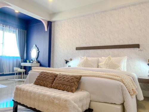 a bedroom with a large white bed and a chair at CRAFT 7th Boutique Nimman in Chiang Mai