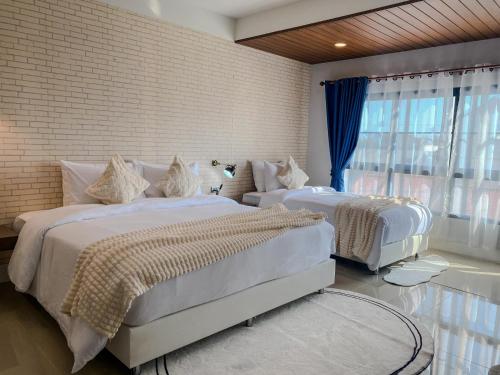 a bedroom with two beds and a brick wall at CRAFT 7th Boutique Nimman in Chiang Mai