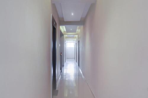 a hallway with white walls and a white floor at Collection O Winds Flower Resort in Pune