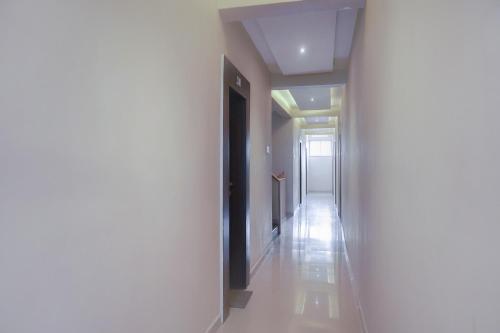 a hallway with a white wall and a white floor at Collection O Winds Flower Resort in Pune