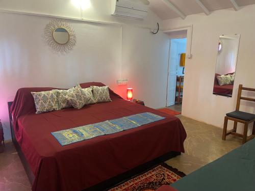 a bedroom with a red bed and a mirror at Art village resort Goa in Canacona