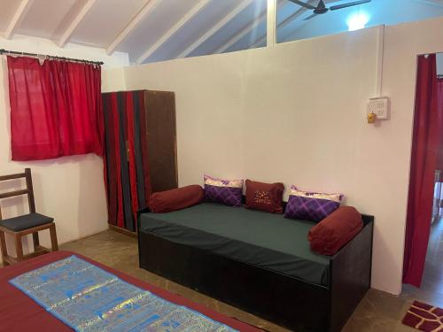 a living room with a couch and red curtains at Art village resort Goa in Canacona
