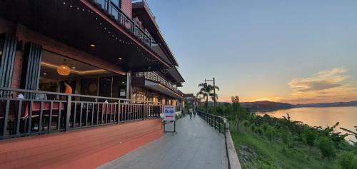 a building with a sidewalk next to a river at Suksomboonhotel in Loei