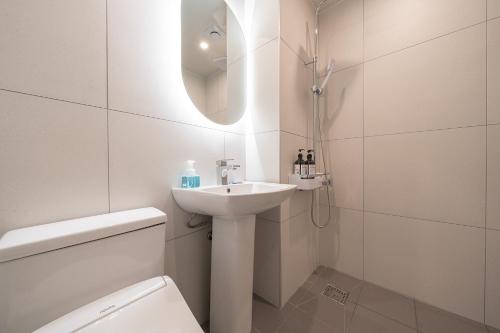 a bathroom with a sink and a toilet and a mirror at Browndot Gangneung Station in Gangneung