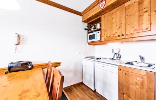 Elle comprend une petite cuisine avec des placards en bois et un évier. dans l'établissement Résidence La Marelle et Le Rami - maeva Home - 2 Pièces 5 Personnes Sélection MAE-1197, à La Plagne Tarentaise