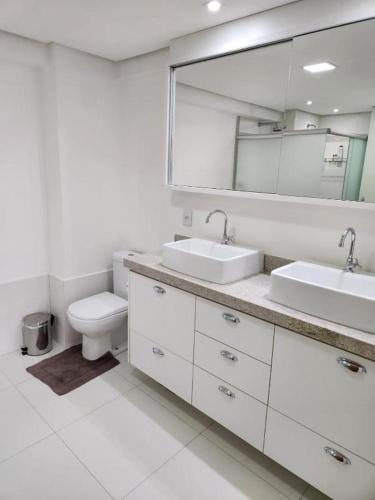 een badkamer met 2 wastafels, een toilet en een spiegel bij INOVA FLAT luxo no Condominio Cosmopolitan in Palmas