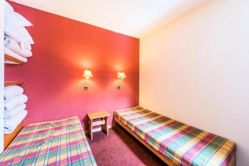 une chambre avec deux lits et un mur rouge dans l'établissement Quartier La Forêt - maeva Home - Appartement 2 Pièces 5 Personnes - Confort MAE-1411, à Valmorel