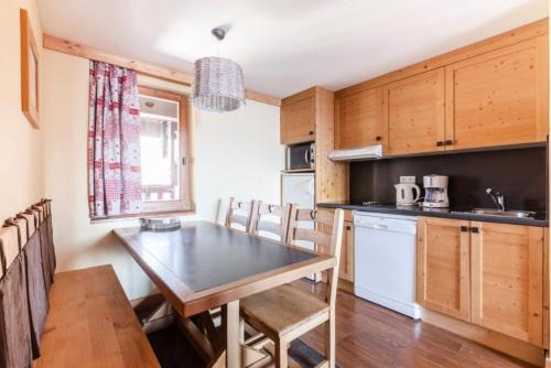 une cuisine avec une table et des chaises dans une pièce dans l'établissement Résidence L'Ours Blanc - maeva Home - 3 Pièces 8 Personnes Prestige MAE-1612, à Huez