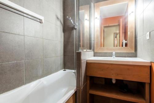 une salle de bain avec une baignoire, un lavabo et un miroir dans l'établissement Résidence L'Ours Blanc - maeva Home - 3 Pièces 8 Personnes Prestige MAE-1612, à Huez