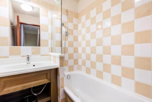 La salle de bains est pourvue d'une baignoire, d'un lavabo et d'un miroir. dans l'établissement Résidence L'Albane - maeva Home - 4 Pièces 9 Personnes Sélection 36, à Vars