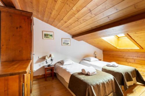 deux lits dans une chambre avec plafonds en bois dans l'établissement Résidence Les Alpages de Chantel - maeva Home - Appartement duplex 3 Pièces 6 Personnes - Sélection MAE-1646, à Bourg-Saint-Maurice