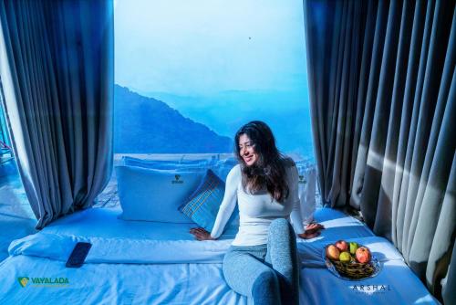 a woman sitting on a bed with a basket of fruit at Vayalada View Point Resort in Kozhikode