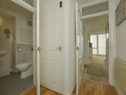 a white bathroom with a toilet and a door at Red Peg in Kingsand
