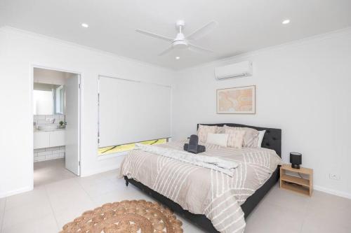 una camera con letto e ventilatore a soffitto di “Brand New Home” Central Charm at Hervey Bay a Urraween
