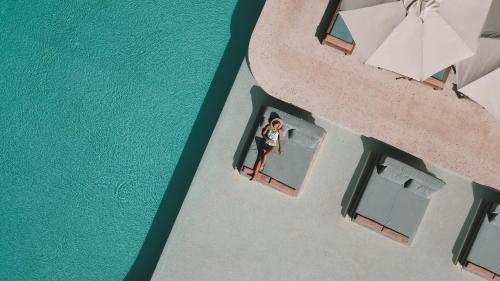 an overhead view of a woman standing in a window next to the water at Perios Beach House - Adults Only in Turunc