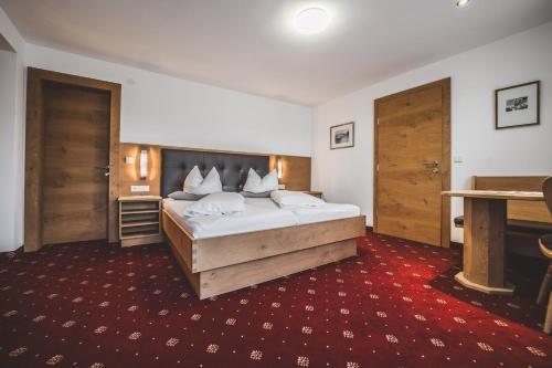 a bedroom with a large bed and wooden doors at Pension Sonnenheim in Schönberg im Stubaital