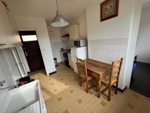 una pequeña cocina con mesa de madera y sillas en Logements Gare Brignoud, en Villard-Bonnot