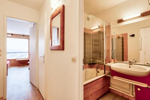 une salle de bain avec un lavabo, une baignoire et un miroir dans l'établissement Résidences quartier Charmettoger - maeva Home - 2 Pièces 5 Personnes Sélection MAE-3657, à Arc 1800