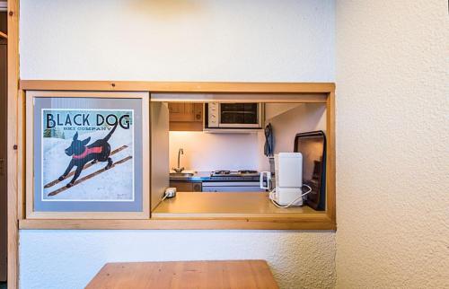 une cuisine avec une photo d'une affiche de chien noir dans l'établissement Quartier Crève Cœur - maeva Home - Studio 4 Personnes Sélection MAE-2006, à Valmorel