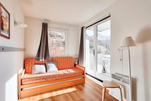 un canapé orange dans une pièce avec une fenêtre dans l'établissement Résidence L'Eyssina - maeva Home - Appartement 3 Pièces 6 Personnes Prestige MAE-3088, à Vars