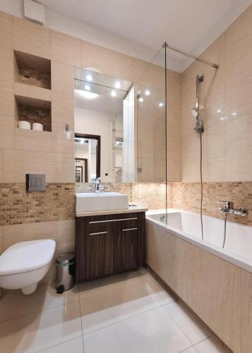 a bathroom with a tub and a toilet and a sink at Chopin Apartments - Platinum Towers in Warsaw