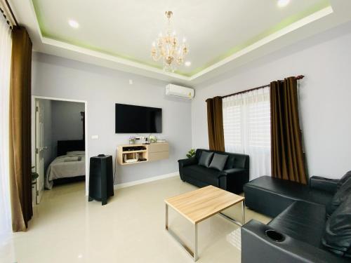 een woonkamer met een bank en een tafel bij Patteera Pool Villa Sattahip in Sattahip