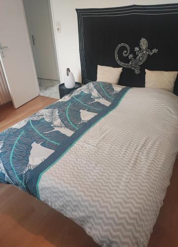 a large bed with a black and white comforter at Appartement quimper in Quimper