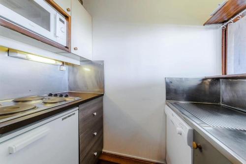 une petite cuisine avec une cuisinière et un micro-ondes dans l'établissement Résidence Les Fontaines Blanches - maeva Home - 2 Pièces 4 Personnes Sélection MAE-5573, à Morzine