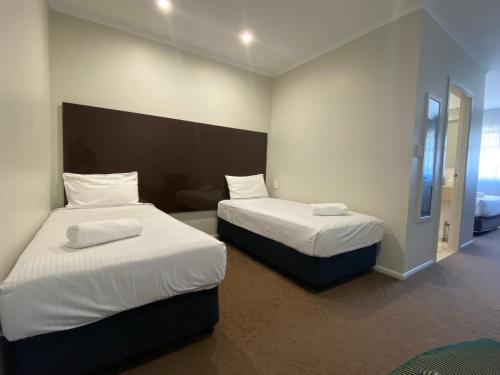 una camera con due letti con lenzuola bianche di Timbertown Motel a Wauchope