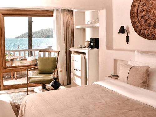 a bedroom with a bed and a chair and a balcony at Perios Beach House - Adults Only in Turunç
