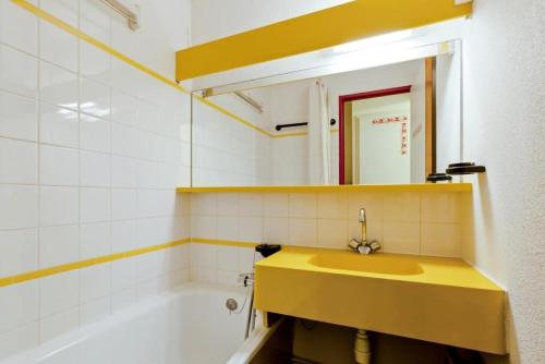La salle de bains est pourvue d'un lavabo jaune et d'une baignoire. dans l'établissement Résidence Les Sentiers du Tueda - maeva Home - 2 Pièces 4 Personnes Confort MAE-4845, à Les Allues