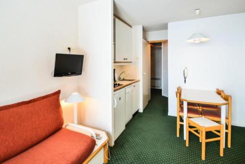 une chambre d'hôtel avec un canapé rouge et une cuisine dans l'établissement Résidence Les Constellations - maeva Home - Studio 5 Personnes Confort MAE-5963, à La Plagne Tarentaise