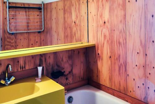 La salle de bains est pourvue d'un lavabo jaune et de murs en bois. dans l'établissement Résidence Les Constellations - maeva Home - Studio 5 Personnes Confort MAE-5963, à La Plagne Tarentaise