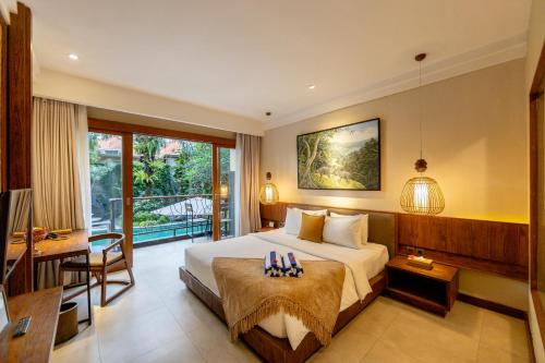 Anumana Ubud Hotel في أوبود: غرفه فندقيه بسرير ومكتب وبلكونه