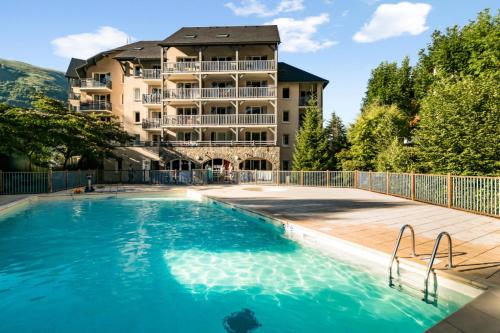 un hotel con piscina frente a un edificio en Résidence Les Rives de L'Aure - maeva Home - 2 Pièces 6 Personnes Sélectio 60, en Saint-Lary-Soulan