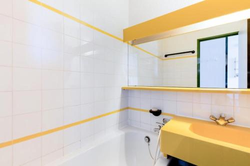La salle de bains est pourvue d'un lavabo jaune et d'un miroir. dans l'établissement Résidence Le Hameau du Sauget - maeva Home - Studio 4 Personnes Confort MAE-4377, à La Plagne Tarentaise