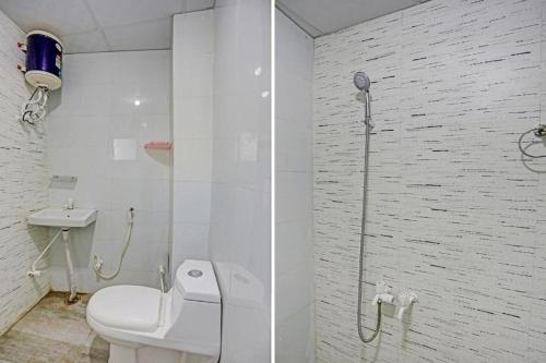 a white bathroom with a toilet and a shower at Umen Hotel Sector 66 in Noida