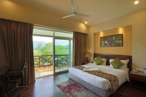 a hotel room with a bed and a balcony at Resort De Coracao - Corbett , Uttarakhand in Rāmnagar