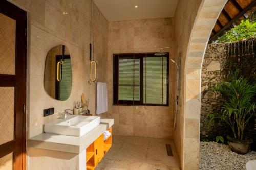 ein Bad mit einem Waschbecken und einem Spiegel in der Unterkunft Oma Ubud in Ubud